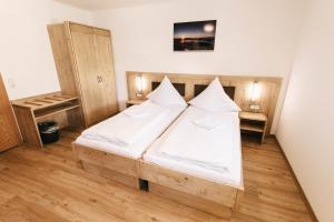 um quarto com uma cama de madeira e lençóis brancos em Gasthof Metzgerei Linsmeier em Iggensbach