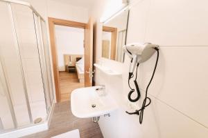 uma casa de banho branca com um chuveiro e um lavatório. em Gasthof Metzgerei Linsmeier em Iggensbach