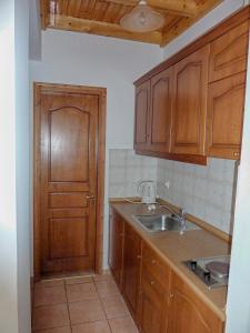 a kitchen with wooden cabinets and a sink and a door at Maria Apartments in Agios Georgios Pagon