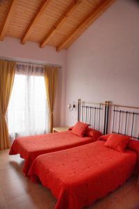 een slaapkamer met 2 bedden met rode lakens en een raam bij Casa Rural Ca'l Gonzalo in Almazán