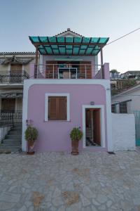 a pink house with two potted plants in front of it at Odysseos St. Loft in Vathi