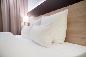 ein Bett mit weißen Kissen darauf in einem Hotelzimmer in der Unterkunft Taste Style Hotel Bären Auggen in Auggen