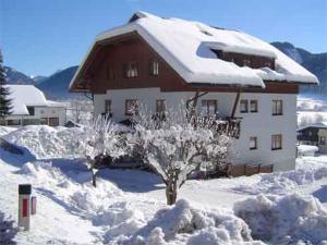 ein schneebedecktes Haus mit einem Baum in der Unterkunft Haus Rohr in Weissensee