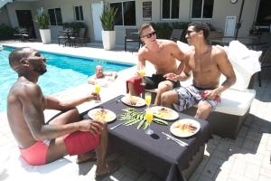a group of men sitting around a table by a pool at The Grand Resort and Spa - All Male Spa Resort in Fort Lauderdale