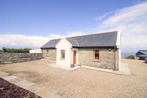 a stone house with a gravel driveway at Salt Cliff Cottage in Doolin
