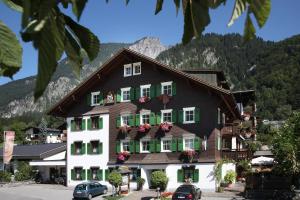 ein Gebäude mit grünen Fensterläden und einem Berg in der Unterkunft Relax & Vitalhotel Adler in Schruns-Tschagguns