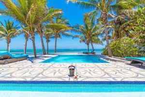 - une piscine avec des palmiers et l'océan dans l'établissement Sprat Bay Luxury Villa, à Half Way Pond