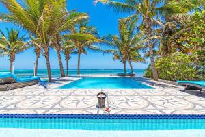 a swimming pool with palm trees and the ocean at Sprat Bay Luxury Villa in Half Way Pond