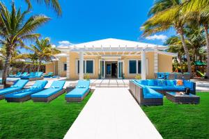 a house with blue chairs and palm trees in front of it at Sprat Bay Luxury Villa in Half Way Pond