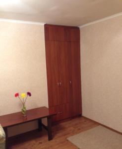 ヴェリーキー・ノヴゴロドにあるApartment on Prusskaya 3の木製のキャビネットと花瓶付きのテーブルが備わる客室です。