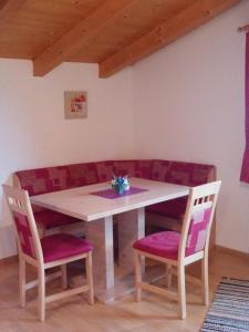a wooden table with two chairs and a table with purple cushions at Haus Franz in Hippach
