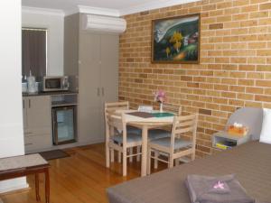 a room with a table and chairs and a brick wall at Palms Oasis Motel in Coopernook
