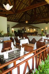 un restaurant avec des chaises en bois et des tables avec des nappes blanches dans l'établissement Cham Villas Resort, à Mui Ne