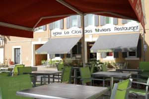un restaurante al aire libre con mesas, sillas y sombrillas en Logis Hotel Le Clos Des Oliviers, en Bourg-Saint-Andéol