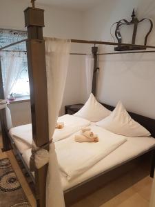 a bed with white sheets and two dolls on it at Hotel Schweizer Stubb in Kaiserslautern