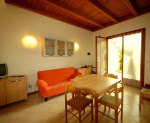 sala de estar con sofá naranja y mesa en Villa Fiori Dalia, en Lido di Pomposa