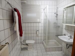 a white tiled bathroom with a toilet and a sink at Ferienwohnung Am Alten Berg in Ochsenfurt