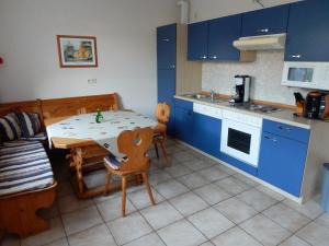 een keuken met blauwe kasten en een tafel en stoelen bij Ferienwohnung Am Alten Berg in Ochsenfurt