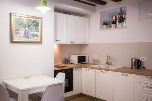 a kitchen with white cabinets and a table and a microwave at Studio apartman Ana in Split +28 photos
