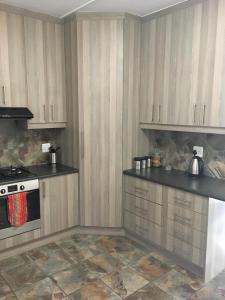 uma cozinha com armários de madeira e um forno com placa de fogão em van Biljon Cottage No Loadshedding em Oudtshoorn