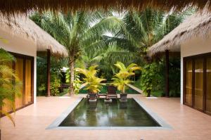 un complexe avec une piscine bordée de chaises et de palmiers dans l'établissement Cham Villas Resort, à Mui Ne