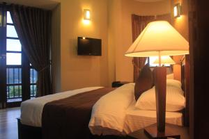 a bedroom with a bed with a lamp on a table at Villa de Roshe in Nuwara Eliya