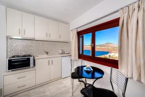 a kitchen with white cabinets and a table and a window at Aspalathos Suites in Akrotiri