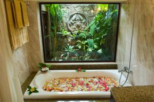 a bath tub filled with flowers in front of a fish tank at Cham Villas Resort in Mui Ne
