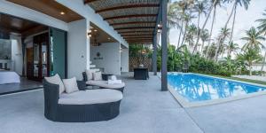 an outdoor patio with chairs and a swimming pool at Bliss Villas in Srithanu