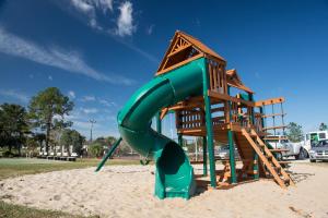 um parque infantil com um escorrega verde na areia em Orlando RV Resort em Orlando