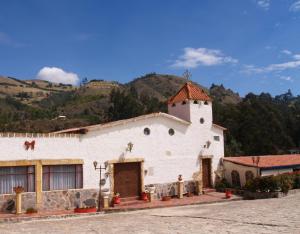eine weiße Kirche mit einem Berg im Hintergrund in der Unterkunft Hotel Rural La Esperanza in Suesca