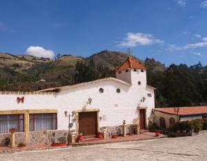 a white church with a mountain in the background at Hotel Rural La Esperanza in Suesca