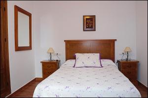 una camera con un letto, due cassettiere e uno specchio di Apartamento Loyola a Conil de la Frontera