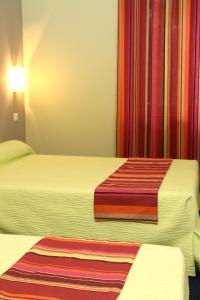 a hotel room with two beds with colorful curtains at Logis Hotel Le Clos Des Oliviers in Bourg-Saint-Andéol +16 photos