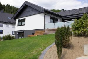 une maison blanche avec une terrasse couverte et une cour dans l'établissement Ferienhaus am Rarbach, à Schmallenberg