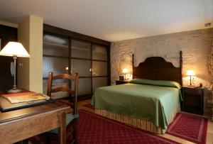 ein Hotelzimmer mit einem Bett und einem Schreibtisch in der Unterkunft Hotel Pazo de Lestrove by Pousadas de Compostela in Padrón