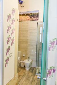 a bathroom with a toilet and a glass shower door at Dammuso di Ponente Ortigia in Siracusa