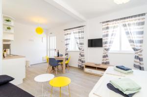 een witte woonkamer met gele stoelen en een tafel bij ABC Lapad Apartments in Dubrovnik