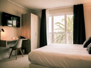 a bedroom with a bed and a desk and a window at Best Western Plus Antibes Riviera in Antibes