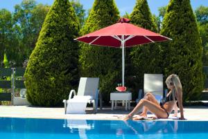 een vrouw in bikini die onder een paraplu naast een zwembad zit bij Verde Al Mare Boutique Hotel in Kalogria
