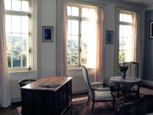 a living room with a table and chairs and windows at Chambres d'Hôtes les Charmettes in Étretat