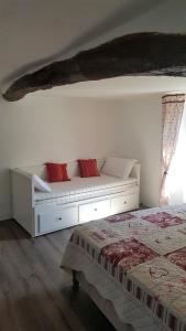 a white bed with red pillows in a bedroom at Gîte - Mas de Louise in Rousson