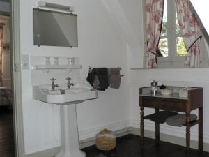 La salle de bains blanche est pourvue d'un lavabo et d'une table. dans l'établissement Chambres d'Hôtes les Charmettes, à Étretat