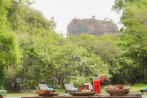 a table with plates of food and a bowl of fruit at Sigiriya Village in Sigiriya