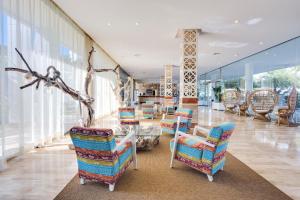a lobby with chairs and a table and a room with windows at Aparthotel Tropic Garden in Santa Eularia des Riu