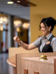 a woman sitting in a restaurant with a bell at Eurostrand Resort Moseltal in Leiwen +31 photos