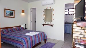 a bedroom with a bed and a mirror and a sink at Pousada Barratur in Florianópolis