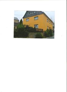 una casa amarilla con techo negro en Siebers-Ferienwohnung, en Saupsdorf