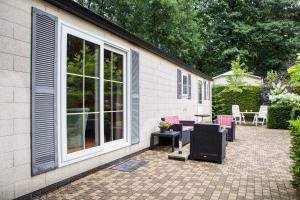 a patio with chairs and tables next to a building at Chalet vakantie Wageningen in Wageningen