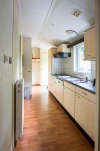 a kitchen with white cabinets and a wooden floor at Chalet vakantie Wageningen in Wageningen